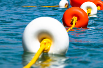 Close-up bright red and white coloers buoys on yellow rope on surface of the water. Depth marks. Safety on the water.