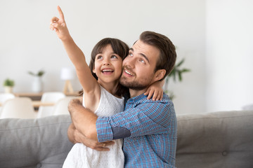 Happy cute daughter show something to smiling young dad