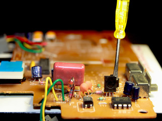 Electrical board with electronic components. High-tech printed circuit board. Screwdriver.