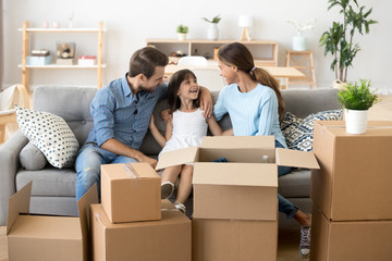 Fototapeta na wymiar Excited parents relax on sofa with daughter on moving day