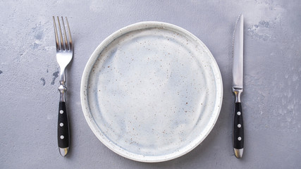 Empty  grey plate with fork and knife. Top view.  Space for text