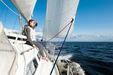 Young girl looking forward sitting on yacht desk having trip