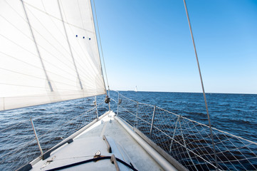 Obraz premium White sailing yacht at a speed swims to shore