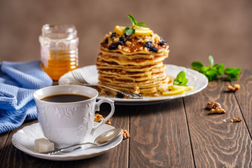 Pancakes with honey, nuts and raisins with a cup of coffee