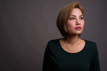 Portrait of beautiful Asian businesswoman against gray background