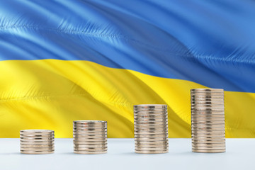 Ukraine flag waving in the background with rows of coins for finance and business concept. Saving money.