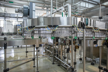 Empty plastic bottles move on automatic conveyor line or belt in water and juice factory or plant...