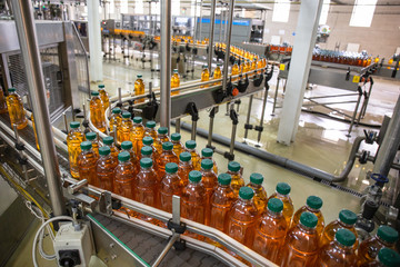 Plastic bottles with juice on automated conveyor line or belt in modern beverage plant or factory production