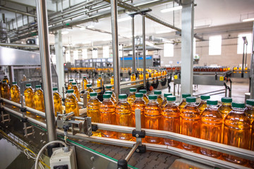 Plastic bottles with juice on automated conveyor line or belt in modern beverage plant or factory production