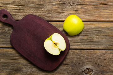 half cut green apple on chopping board, old wooden table
