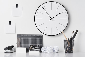 Office supplies and wall clock on white