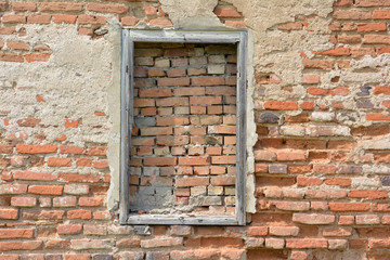 Fototapeta na wymiar A bricked window with wooden frame on the wall of red brick