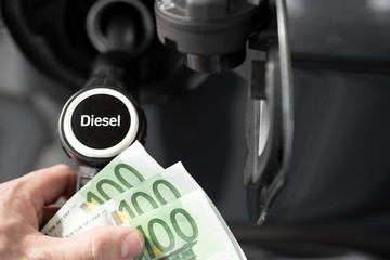 Tanken und Autofahren wird teuerer, Mann mit Geldscheinen an der Zapfsäule an der Tankstelle