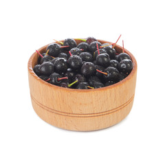 heap of black chokecherry in wooden cup isolated on white