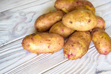 Raw whole washed organic potatoes on sackcloth over old wooden plank background. Top view with space