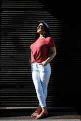 Young pretty brunette walking around the city on a sunny day, dressed in summer clothes, and a hat on her head. Summer style