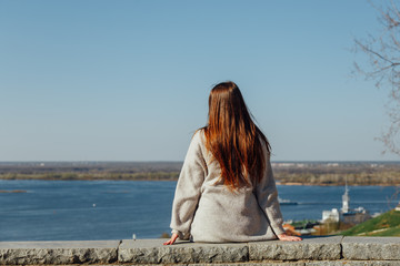 Rear view young long hair girl looking at the river. Space and space for text, beautiful view.