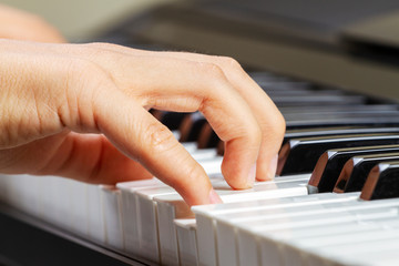 Close up view of kid hands playing on piano keyboard