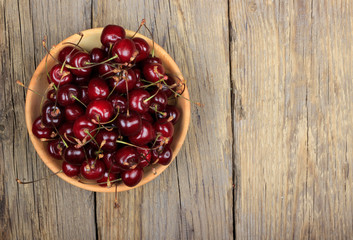 cherry in wooden plate on wooden background