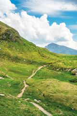 path uphill to the mountain top. beautiful summer scenery with dynamic cloud formations on a blue...