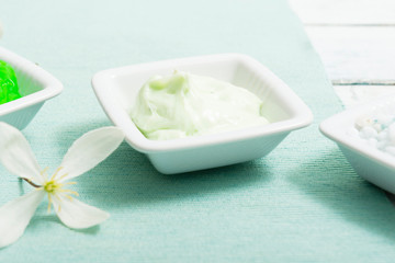 cosmetic creams and white flower, on textile, white painted wooden