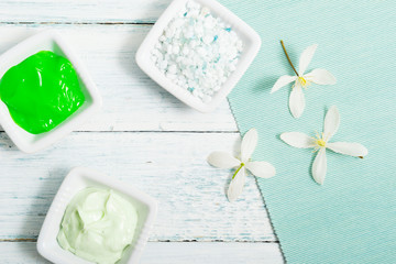 cosmetic creams and white flower, on textile, white painted wooden