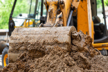 Fototapeta na wymiar Excavator bucket pours ground. Repair work plumbing.