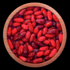 barberry in wooden cup isolated on black background. top view