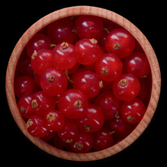 heap of red currant in wooden cup isolated on black. top view