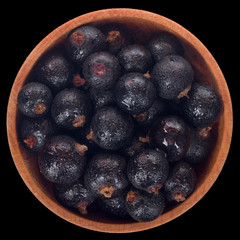 heap of black currant in wooden cup isolated on black. top view