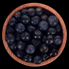 heap of bilberry in wooden cup isolated on black. top view