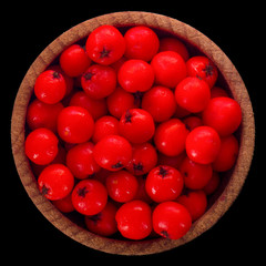 heap of red ashberry in wooden cup isolated on black background. top view