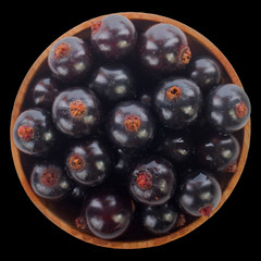 heap of black currant in wooden cup isolated on black. top view