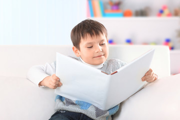 preschooler reading a book on the couch in the nursery