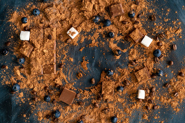 top view of the cocoa powder on the dark table flat lay, chocolate and sugar background and copy spaces