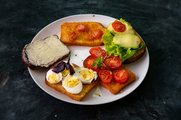 white ceramic plate with set of sandwiches with avocado, eggs, butter, tomato and jams