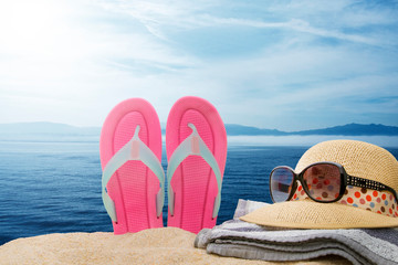 sandals with hats and sunglasses on the beach with the sea