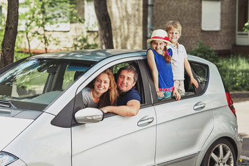 family with two children sitting in their family car.