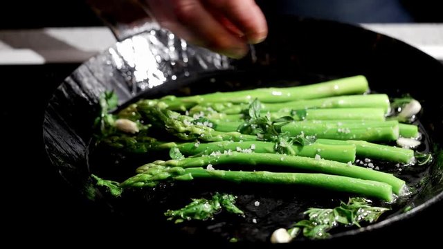 putting salt on green asparagus