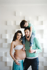 Fototapeta premium Happy family waiting for a second child. Last months of pregnancy. Pregnant woman with husband and little boy . Second pregnancy, maternity concept.