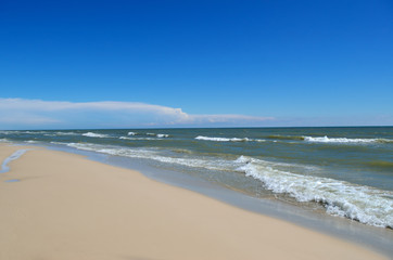 Fototapeta na wymiar Sea waves wash the clean sandy beach. Landscape on a wild beach. The sea in the summer.