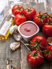 Ketchup or tomato sauce, olive oil, garlic and fresh tomatoes on a branch against a rustic background.