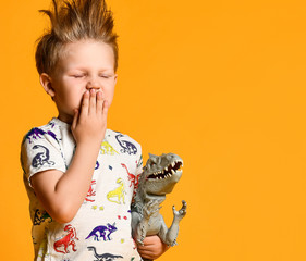 little boy with a funny, disheveled hair holds the toy plastic dinosaur as a portrait.