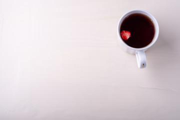 Copy space hot cup of tea with strawberry fruit isolated on white background