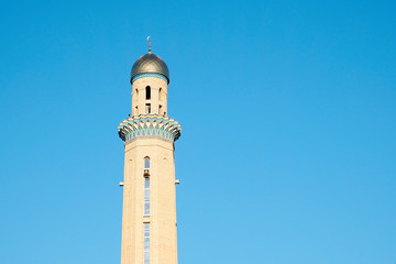 Fototapeta premium The Golden minaret of the mosque. Muslim symbol on blue sky background. Crescent. Sunset. The concept of religion.