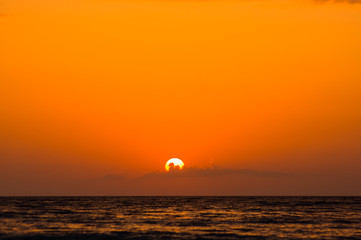 Amazing sea sunset on the pebble beach, the sun, waves, clouds