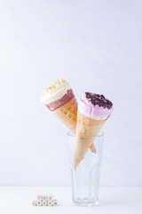 Ice cream with chocolate and nuts on a white background. Two ice cream cones in a glass. Summer milk dessert in a waffle cone. Copy space