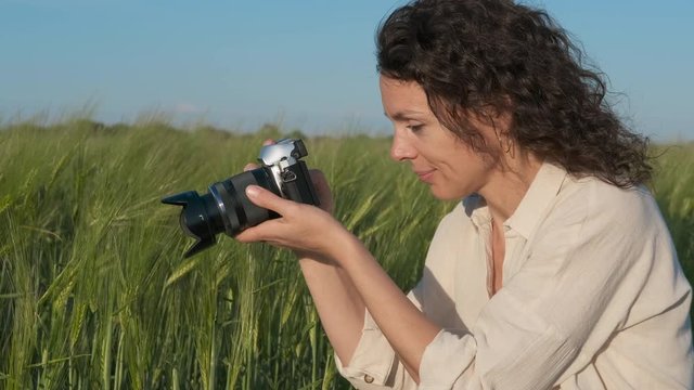 A female photographer takes pictures in nature. A woman takes a picture in a wheat field.