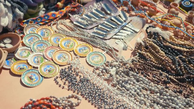 Handmade artisan collars and souvenirs over a table for sale in an Argentinian street market.