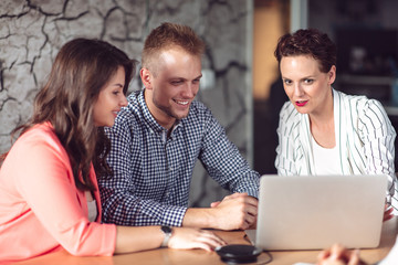 Investment adviser giving a presentation to a friendly smiling young couple seated at her desk in the office